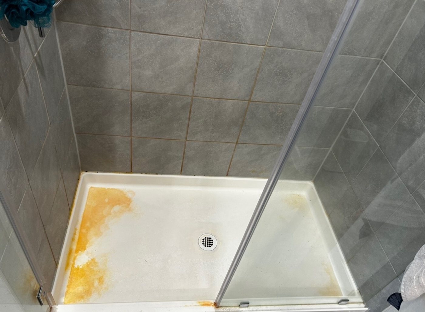 Shower pan before cleaning — rust and hard-water stains